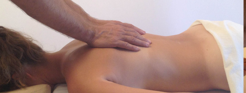 Two hands applying massage to the back.